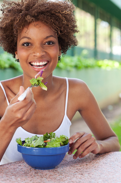 Pretty African American woman eating a salad - Фото, зображення