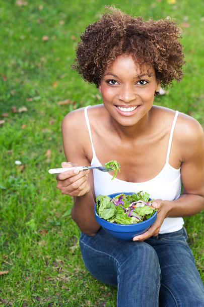 Pretty African American woman eating a salad - Фото, зображення