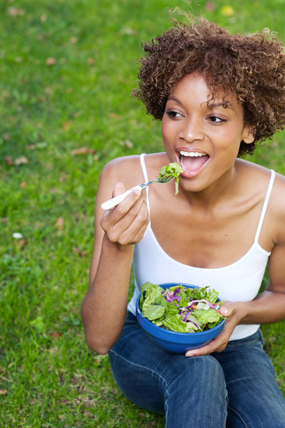 vrij african american vrouw eten van een salade - Foto, afbeelding