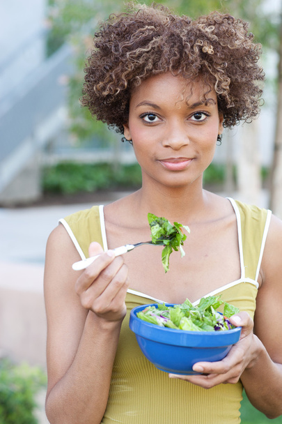 vrij african american vrouw eten van een salade - Foto, afbeelding