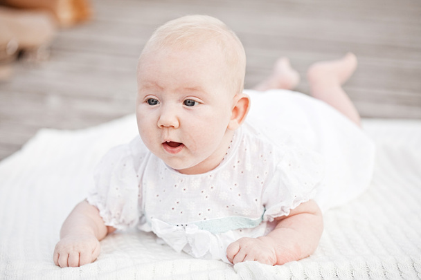 Niño bebé acostado feliz sonriendo en la manta de punto sobre un fondo blanco
 - Foto, imagen
