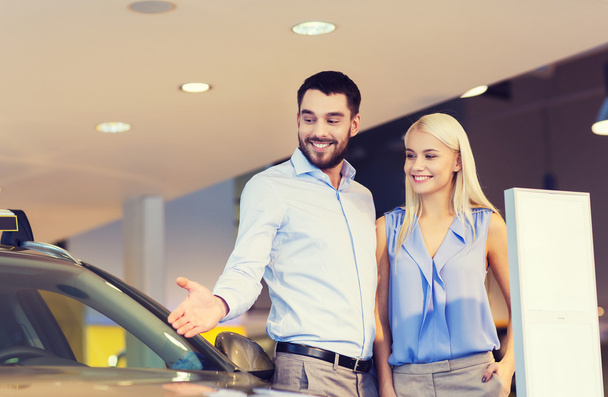 happy couple buying car in auto show or salon - Foto, immagini