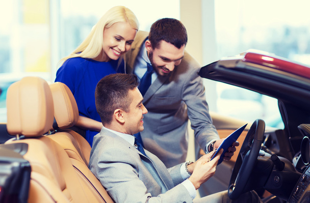 happy couple with car dealer in auto show or salon - Foto, Bild