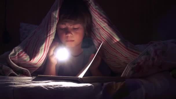 child reading a book under the covers - Materiał filmowy, wideo