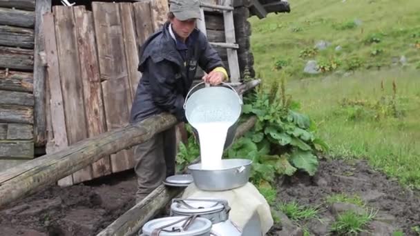 boer giet melk uit een emmer in de barrel - Video