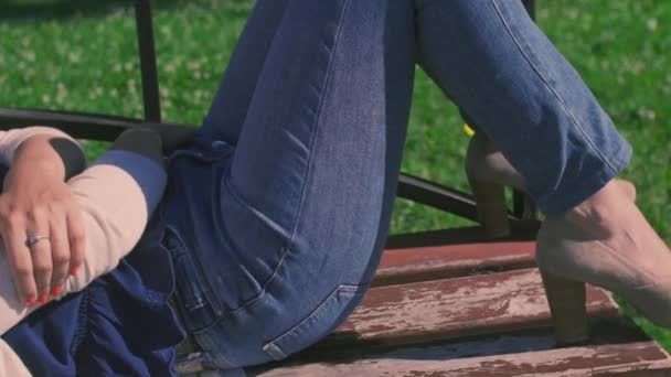 Κορίτσι και βρίσκεται σε μια περιτύλιξη chez τον άνθρωπο στο πάρκο σε ένα παγκάκι - Πλάνα, βίντεο
