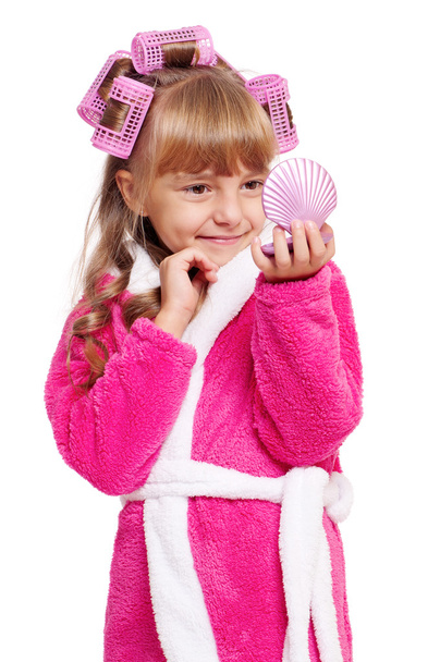 Little girl in pink bathrobe looking into a mirror - Фото, изображение