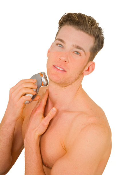 Young man shaves with electric razor - Φωτογραφία, εικόνα