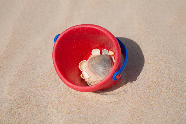 seau rouge sur sable avec coquillages
 - Photo, image
