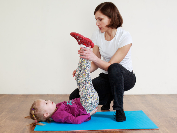 Trainer  is doing back exercise with a little girl - Foto, afbeelding