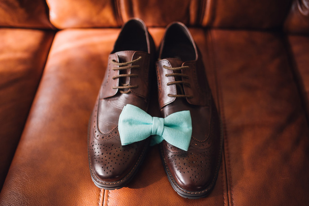 Zapatos para hombre y pajarita sobre fondo de cuero marrón
  - Foto, imagen