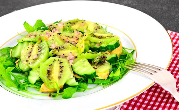 Arugula salad, kiwi and cucumber on white plate. - Photo, Image