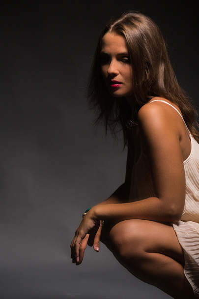The romantic image of the beautiful brunette in a delicate white dress against a dark background. - Photo, Image