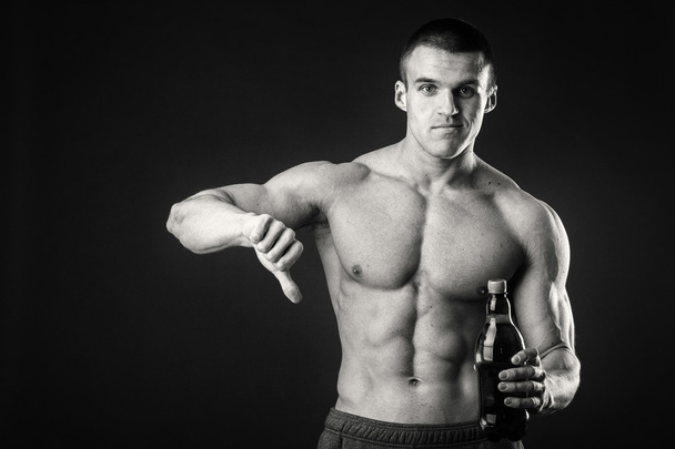 Mannelijke bodybuilder laat zien dat bier slecht is. - Foto, afbeelding