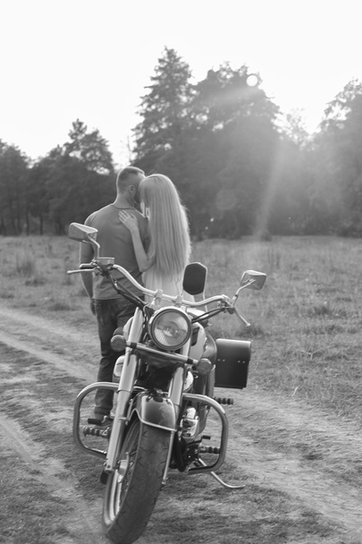 Μαύρο και άσπρο φωτογραφία ποδηλάτης ζευγάρι σε μια μοτοσικλέτα στο πεδίο. - Φωτογραφία, εικόνα