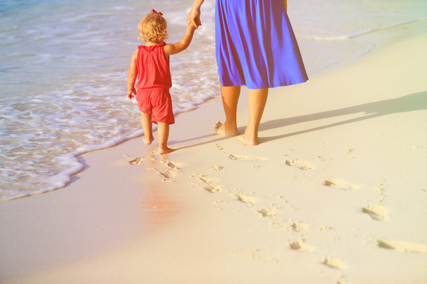 mother and daughter walking on beach leaving footprint in  sand - Photo, Image
