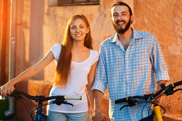 happy young couple of bicyclists talking in the street - Фото, изображение