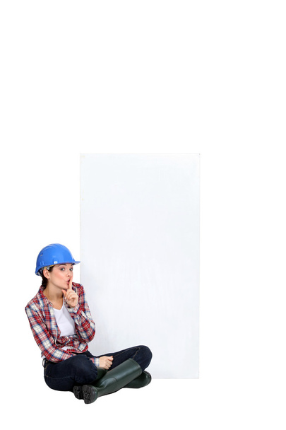 Tradeswoman sitting cross-legged by an empty sign - Fotografie, Obrázek