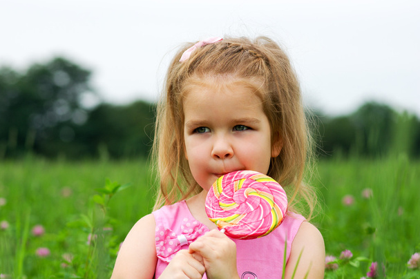  Το κοριτσάκι τρώει ένα γλειφιτζούρι. - Φωτογραφία, εικόνα