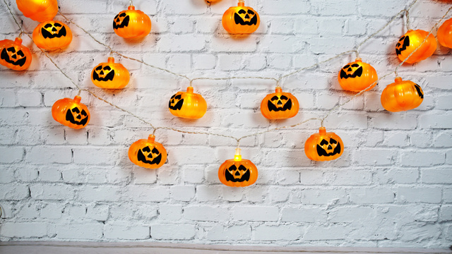 Designvorlage Bright Jack-o'-lanterns Garland On Brick Wall For Halloween für Zoom Background